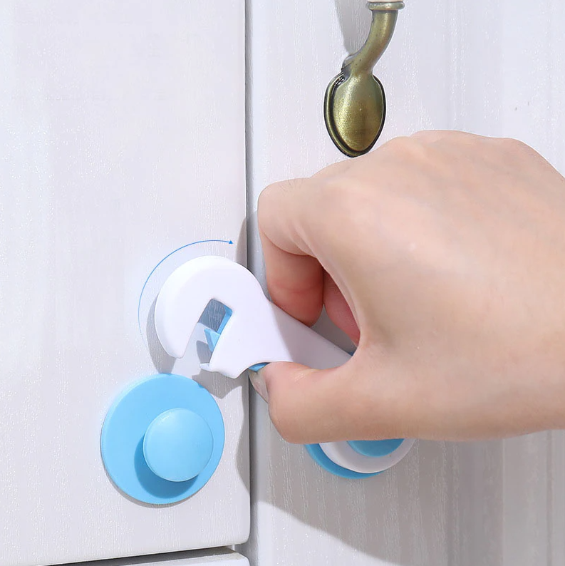 hand holding a cabinet safety locks attached to the cabinet door