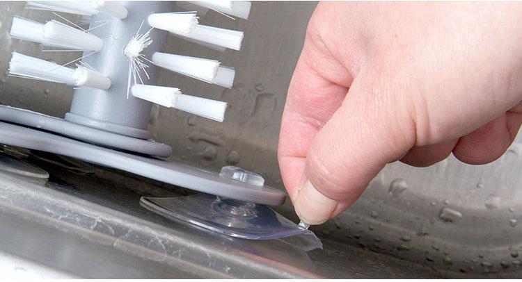 hand attaching the glass cleaning bush on the kitchen sink using the suction adhesive