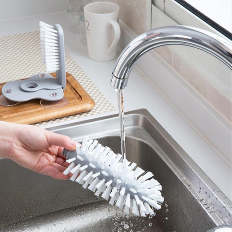 hand holding a glass cleaning brush in running water from the faucet