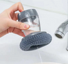 hand holding a soap dispensing palm brush  while pressing the mini tank button 