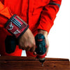 man wearing an orange outfit holding a drilling tool with magnetic wristband  