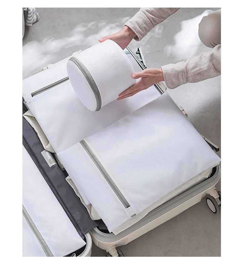 hand holding a bra bag and mesh laundry bag arranged inside a travel bag